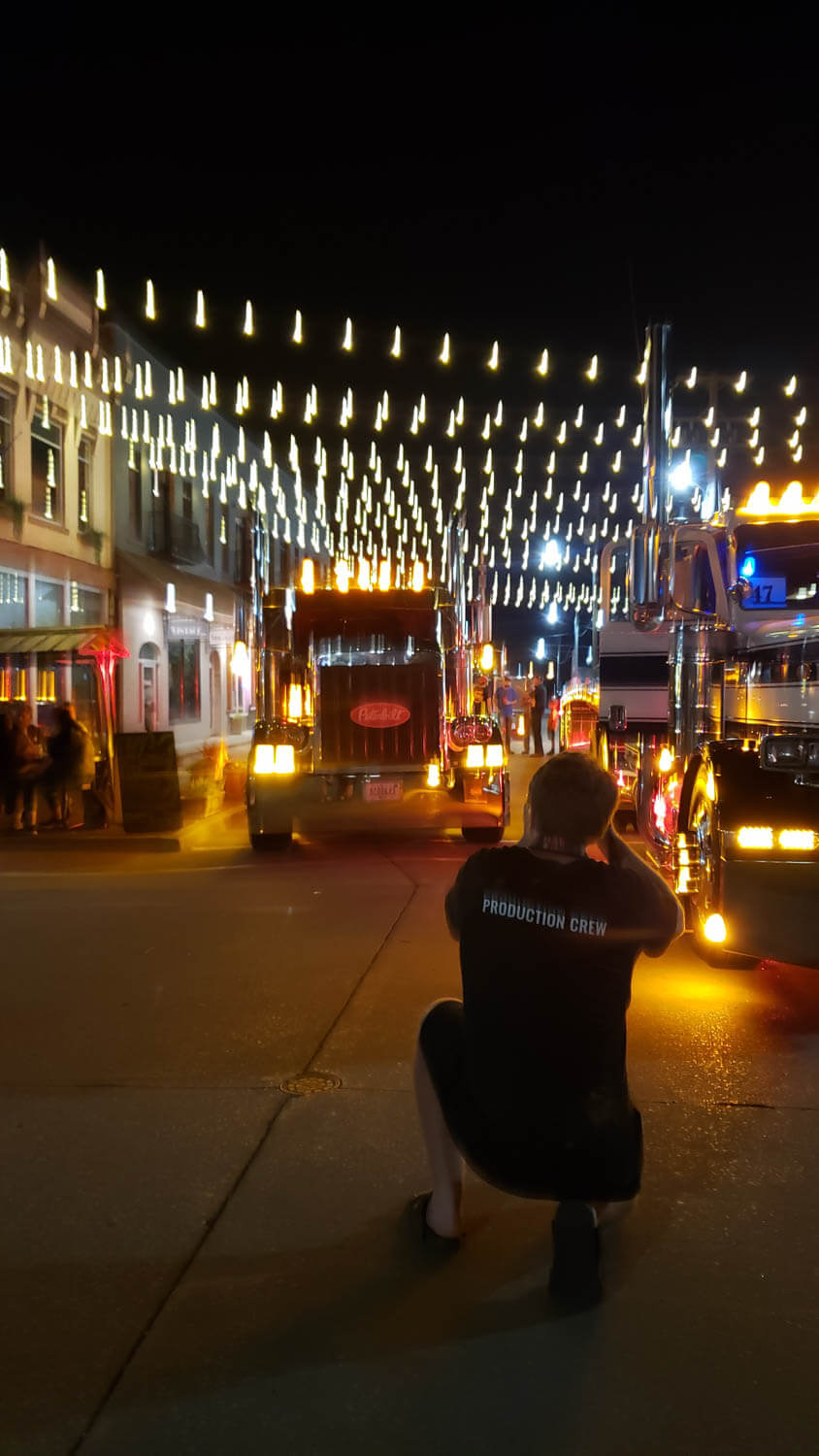 lit mainstreet at night with a bunch of semi trucks