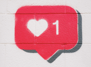 social media comment bubble with a heart inside painted on white brick