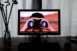 photos on a computer monitor of a man with binoculars with the Facebook logo on them